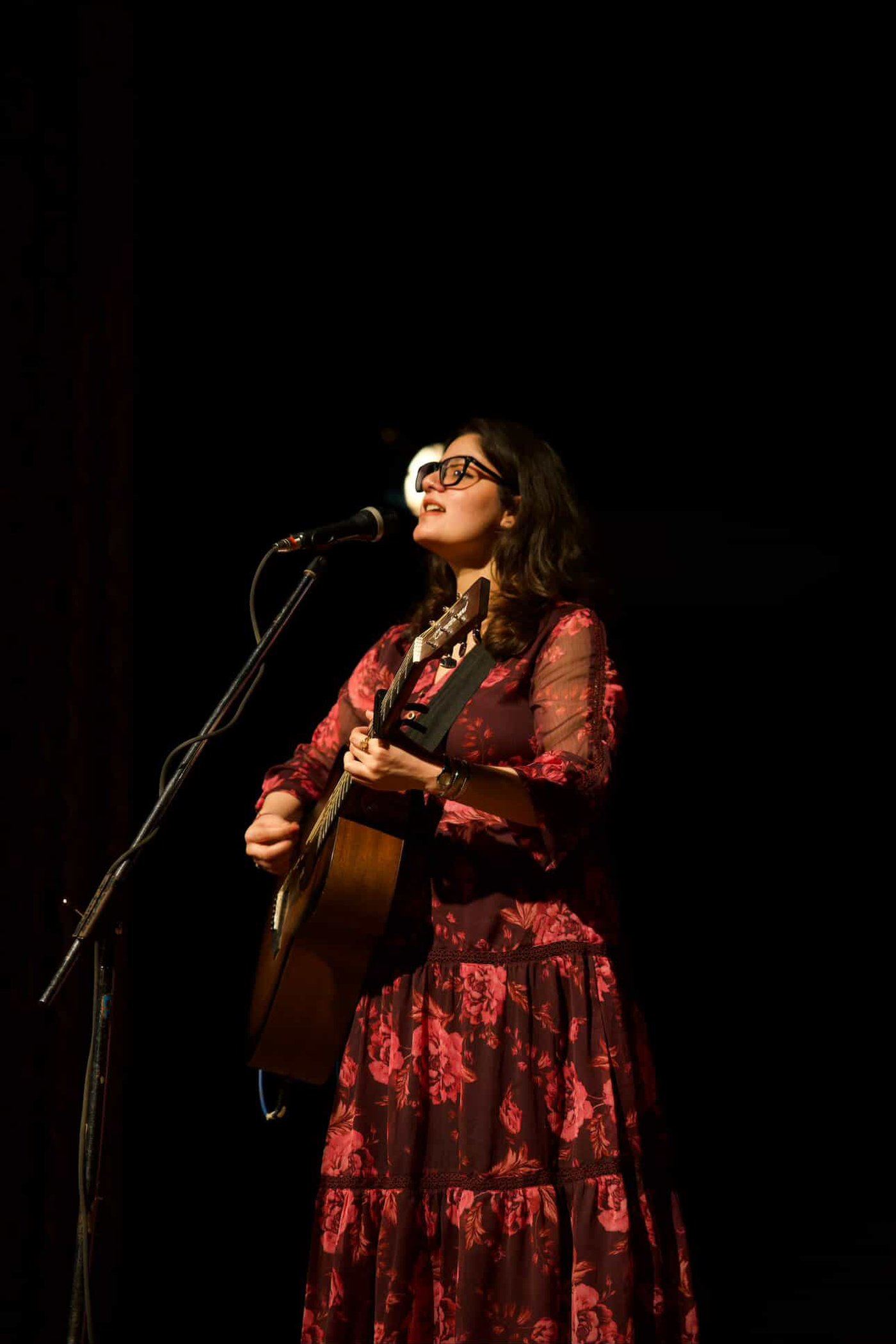 Fiza Sharma, Founder of The Sound Theory, performing on stage with an acoustic guitar